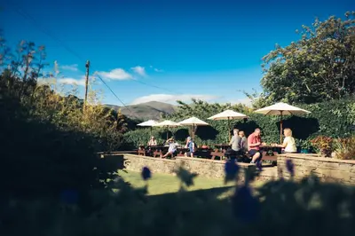 a group of people sitting at tables with umbrellas at The Coledale Inn in Keswick