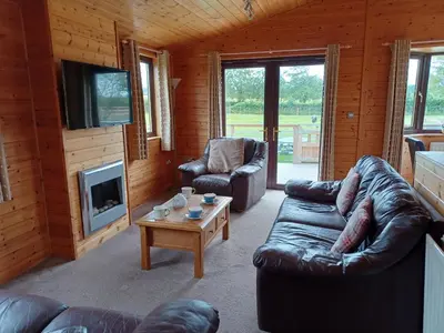 a living room with couches and a tv and a fireplace at Green View Lodges in Wigton
