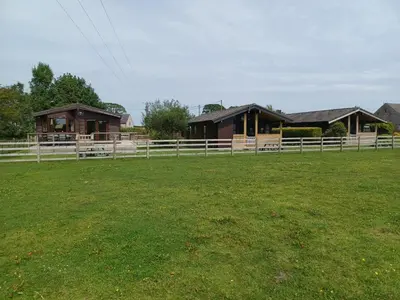 a group of buildings in a field with a fence at Green View Lodges in Wigton