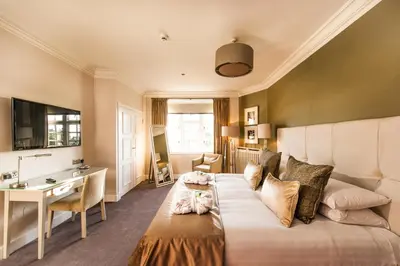 a room with a large bed with a desk and a desk at Piersland House in Troon