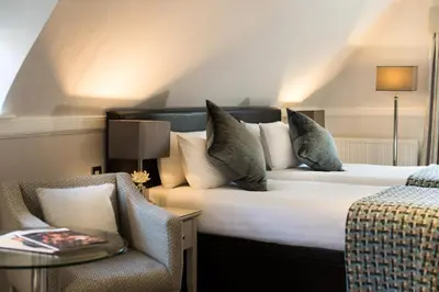 a hotel room with a bed and a chair at Piersland House in Troon