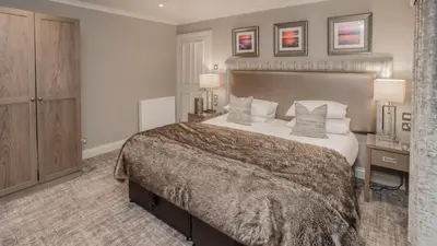 a large bedroom with a large bed and two lamps at Piersland House in Troon