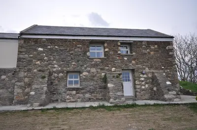a stone house with two windows on the side of it at The Barn at Ballaloaghtan in Ballasalla