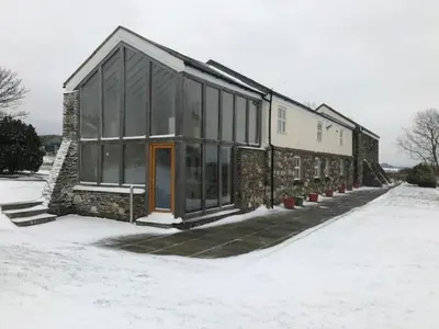 a building with glass windows in the snow at The Barn at Ballaloaghtan in Ballasalla