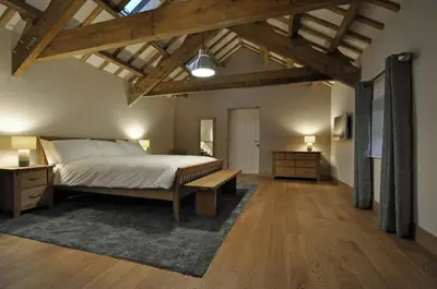 a bedroom with a large bed and a wooden ceiling at The Barn at Ballaloaghtan in Ballasalla