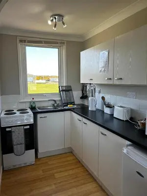 a kitchen with white cabinets and a window at Burrowhead Holiday Village in Isle of Whithorn