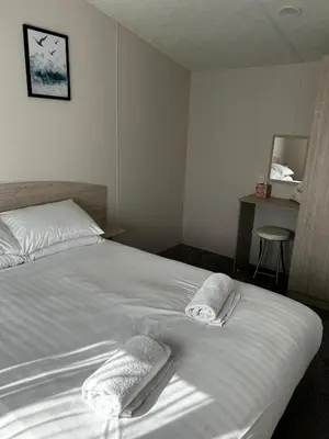 a bedroom with a white bed with towels on it at Burrowhead Holiday Village in Isle of Whithorn
