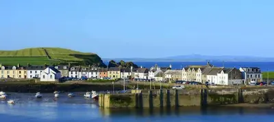 a town with houses and boats in the water at Burrowhead Holiday Village in Isle of Whithorn