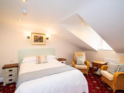 a bedroom with a bed and two chairs at Old Posting House in Cockermouth