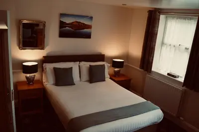 a bedroom with a large bed with two lamps on tables at Old Posting House in Cockermouth