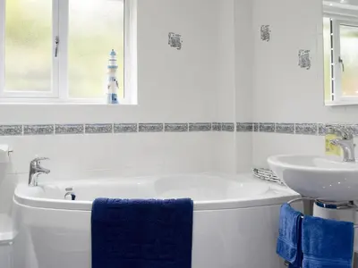a white bathroom with a tub and a sink at Brandelhow in Keswick