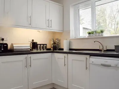 a white kitchen with white cabinets and a sink at Brandelhow in Keswick