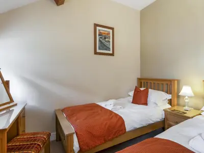 a hotel room with two beds and a chair at Tommy's Cottage in Keswick