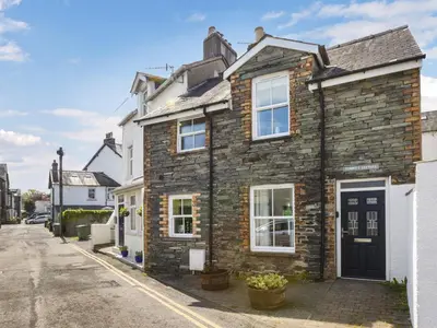 a stone house with a black door on a street at Tommy's Cottage in Keswick