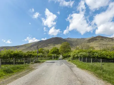 an empty road with mountains in the background at Tommy's Cottage in Keswick