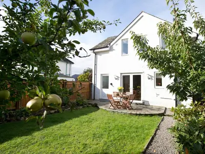 a backyard with a white house and a table and chairs at Elmcot in Keswick