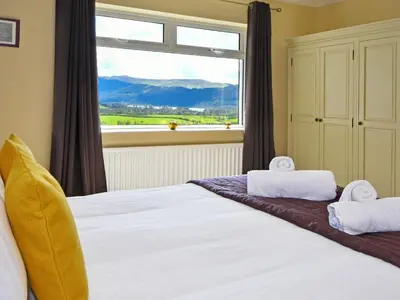 a bedroom with a large bed with a large window at Holly Bank in Bassenthwaite