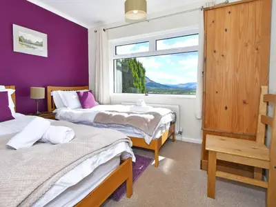 two beds in a room with purple walls and a window at Holly Bank in Bassenthwaite