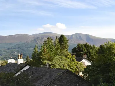 a view of mountains with roofs of houses and trees at Fairholme in Braithwaite