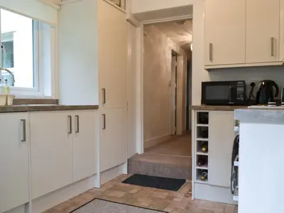 a kitchen with white cabinets and a hallway at Fairholme in Braithwaite