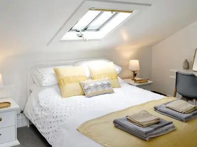 a bedroom with a white bed with a skylight at Loft 10 in Keswick