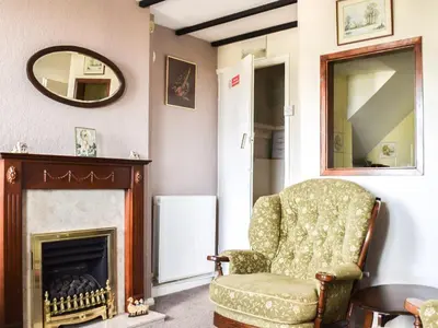 a living room with a chair and a mirror at Cosy Cottage in Allonby