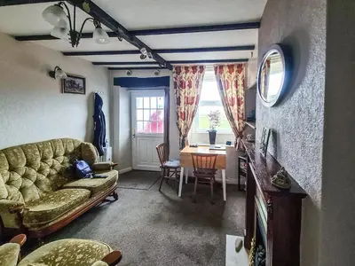 a living room with a couch and a table at Cosy Cottage in Allonby