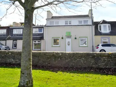 a large white house with a stone wall at Park View Cottage in Stranraer