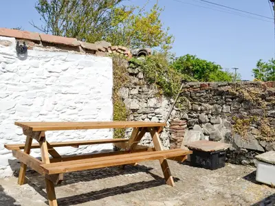a wooden bench sitting next to a stone wall at Mill Street in Drummore