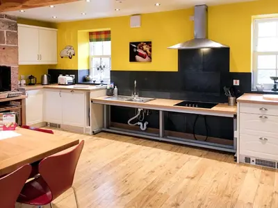 a kitchen with yellow walls and white cabinets and a sink at The Moat House in Annan