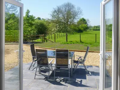 a table and chairs on a patio with a view of a field at Riverside Cottage in Boreland