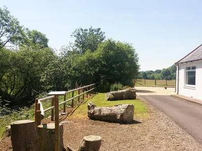 a fence and logs on the side of a road at Riverside Cottage in Boreland