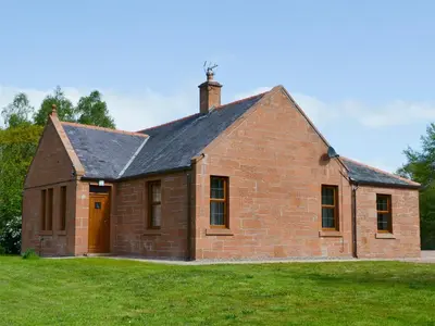 a brick house with a chimney on top of a field at Perch Hall Cottage in Dinwoodie Mains