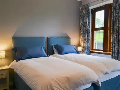 a bedroom with two beds with blue and white at Perch Hall Cottage in Dinwoodie Mains