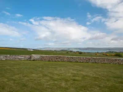 a stone wall in the middle of a field at Quarter Acre House in Challoch