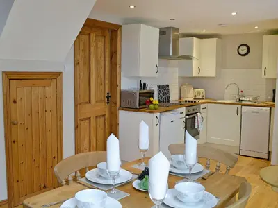 a kitchen with a wooden table with chairs and a dining room at Aden Barn in Allonby