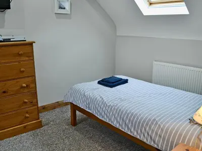 a small bedroom with a bed and a dresser at Aden Barn in Allonby