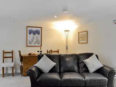 a living room with a leather couch and a table at Hameish Holiday Cottage in Kirkcudbright