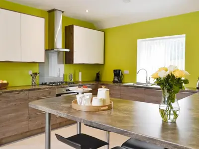 a kitchen with a table with a vase of flowers at Hameish Holiday Cottage in Kirkcudbright