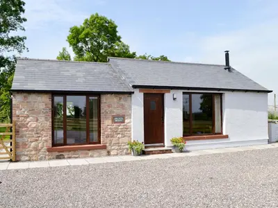 a small stone cottage with a door and windows at Bruno's Bothy in Wigton