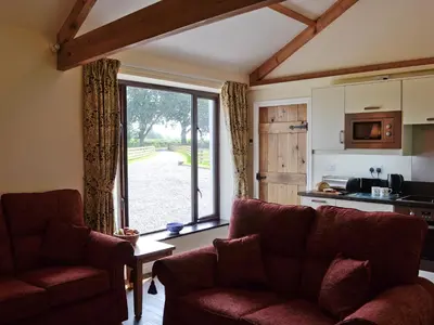 a living room with a couch and a large window at Bruno's Bothy in Wigton