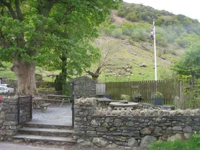 a stone wall with a bench and a tree at The Langstrath Country Inn in Keswick