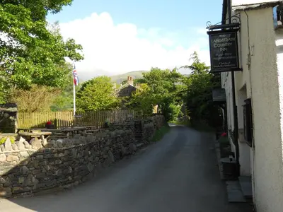 a street with a stone wall next to a building at The Langstrath Country Inn in Keswick