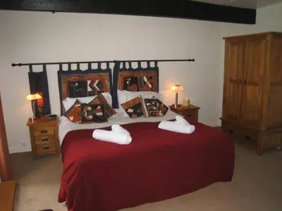 a bedroom with a large bed with red sheets and pillows at The Langstrath Country Inn in Keswick