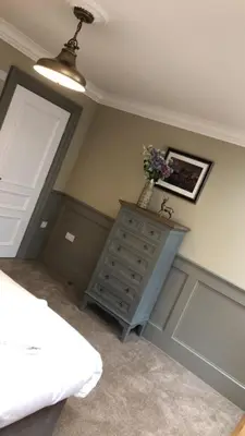 a bedroom with a bed and a dresser with flowers on it at The Huntingdon in Dumfries