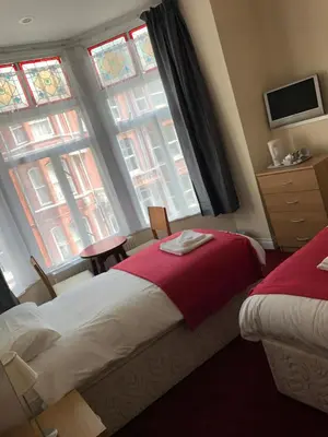 a hotel room with two beds and two windows at Glenfaba Guest House in Douglas