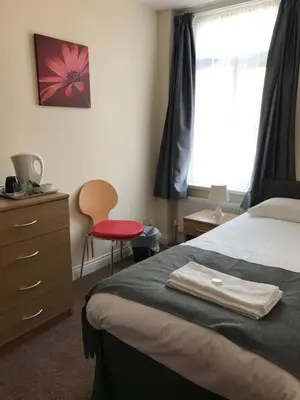 a bedroom with a bed and a dresser and a window at Glenfaba Guest House in Douglas