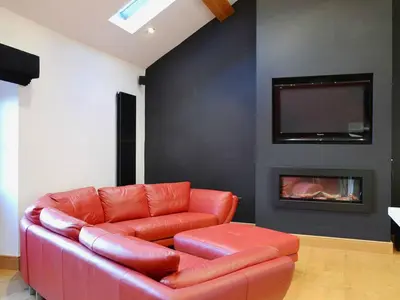 a red leather couch in a living room with a fireplace at Saddleback Penthouse in Penrith