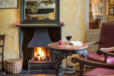 a fireplace in a room with a table and a glass of wine at The Traveller's Rest in Grasmere