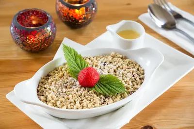 a bowl ofatmeal with a strawberry on a table at The Traveller's Rest in Grasmere